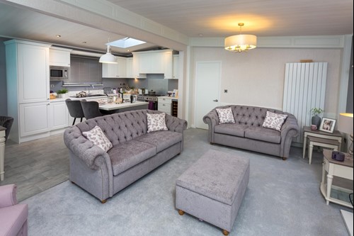 old-fashioned yet modern caravan lounge, with soft chesterfield couches and a grey/white colour scheme