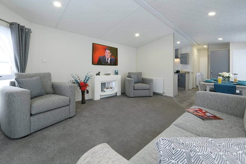 best caravan manufacturer Delta's caravan lounge, with two armchairs, a wall-mounted tv, and grey/white decor