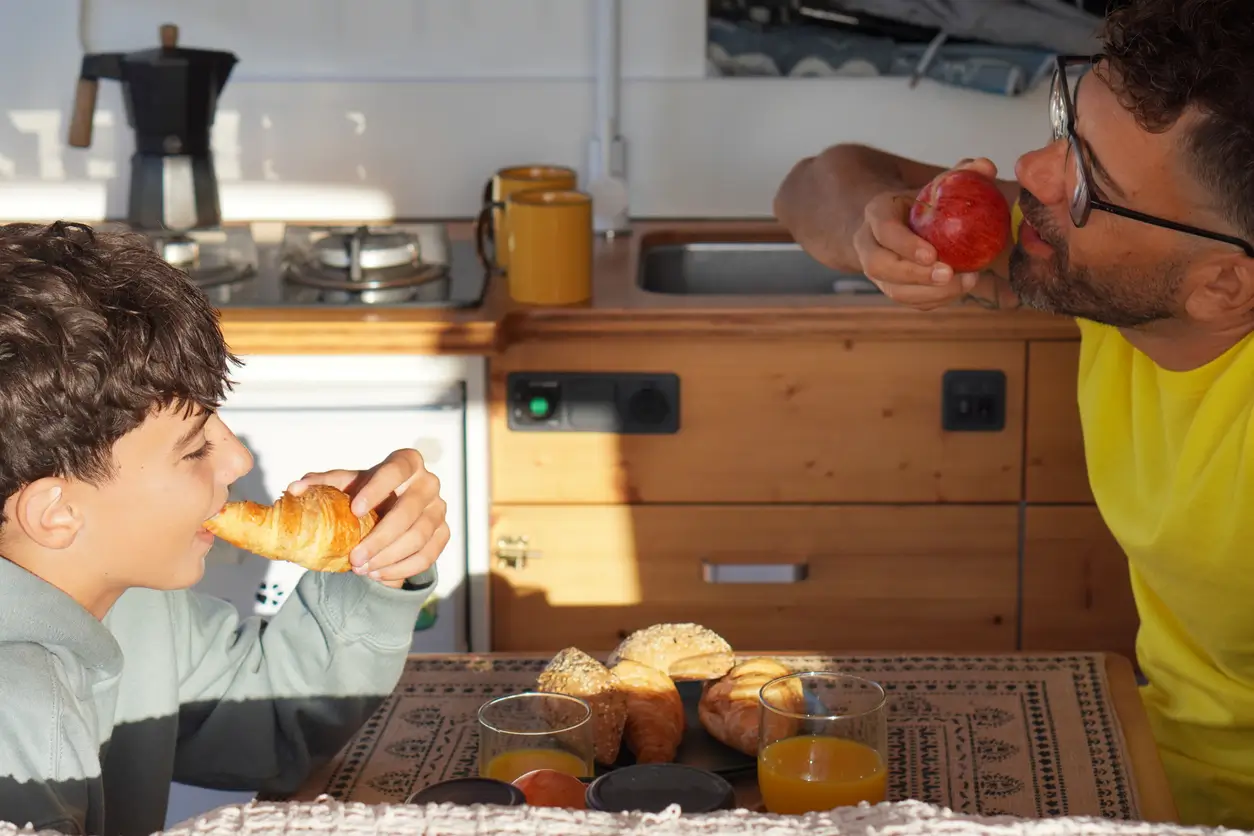 dad and son eating breakfast in a caravan