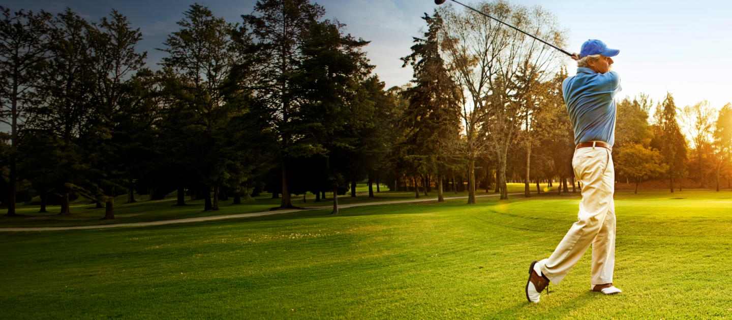 Man swinging golf club on golf course 