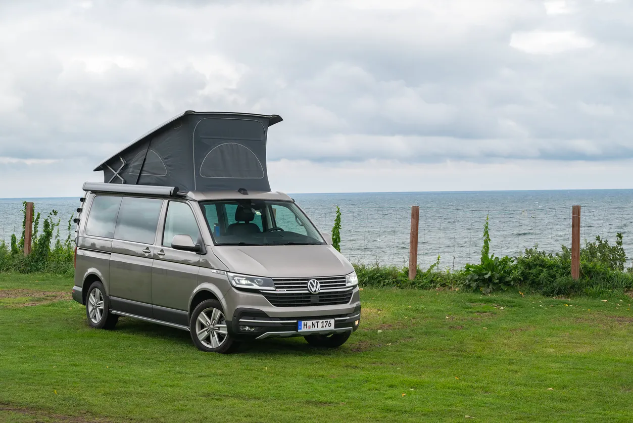 VW campervan parked on the grass near the beach