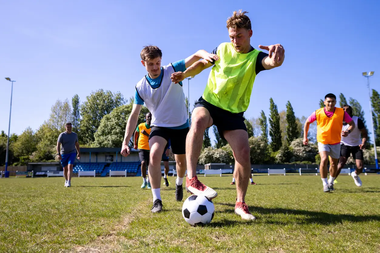Two footballers running a drill and going into a tackle