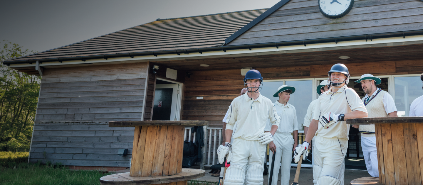 Cricket team stood up waiting by the clubhouse